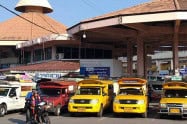 View of Chiang Mai bus station with yellow taxis and buses parked outside.