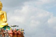 Large golden Buddha statue with a cloudy sky background.