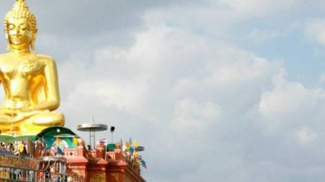 Large golden Buddha statue with a cloudy sky background.