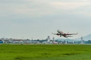 Airplane taking off from Chiang Rai Airport with control tower and terminal in background.