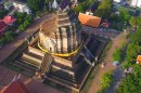 Aerial view of a historic temple with a central chedi in Chiang Mai, Thailand, surrounded by trees.