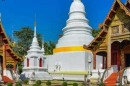 Traditional Thai temple with ornate roofs and white chedi in Chiang Mai.