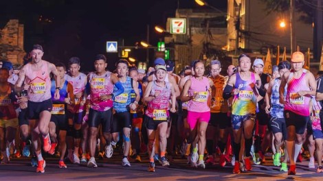 Runners start the Chiang Mai Marathon under a large inflatable arch at night.