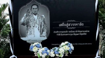 Memorial plaque with a portrait of King Bhumibol Adulyadej surrounded by flowers and greenery.