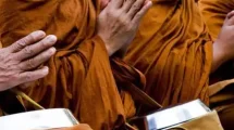 Monks in orange robes praying during Wan Awk Phansa festival in Chiang Mai.