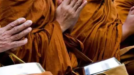 Monks in orange robes praying during Wan Awk Phansa festival in Chiang Mai.